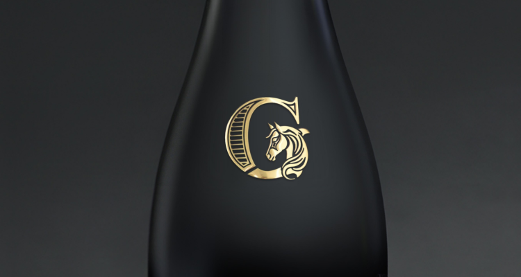 Logo de champagne en transprint or brillant collé sur bouteille. Gros plan sur détails fins du relief.