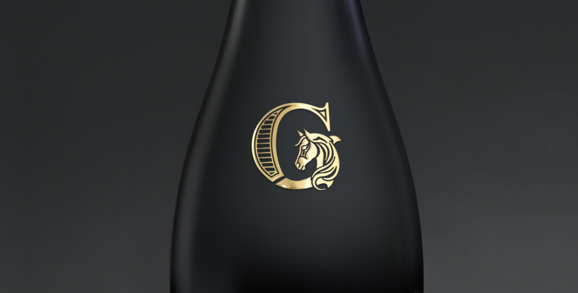 Logo de champagne en transprint or brillant collé sur bouteille. Gros plan sur détails fins du relief.